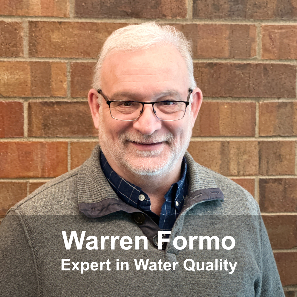 Senior man with glasses smiling against brick wall